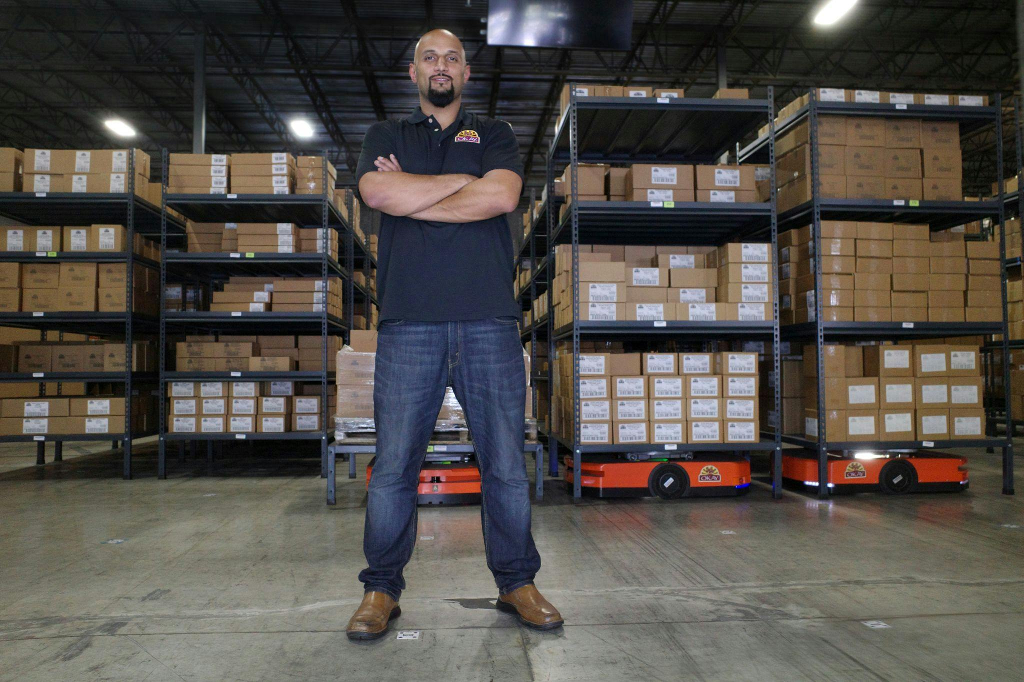 Co-Founder & VP Osman Mithavayani in the Okay warehouse in front of the robotic pallets